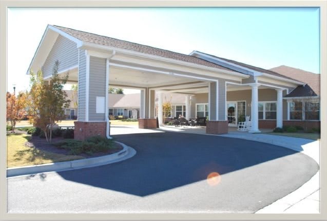 A covered entrance to a facility with a circular driveway.