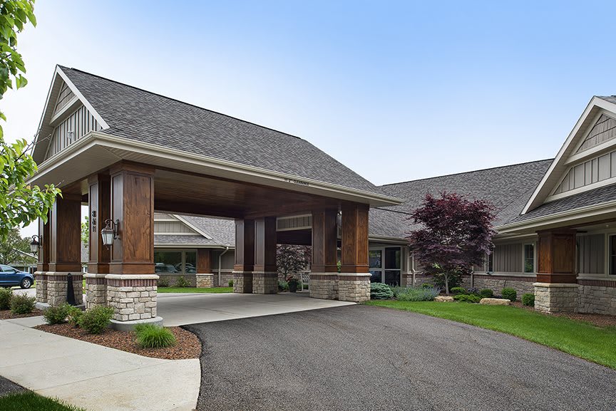 A modern building entrance with a covered driveway and landscaped surroundings.