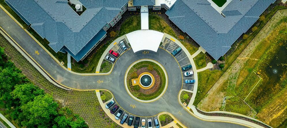 Aerial view of a building complex with a circular driveway and parking area.