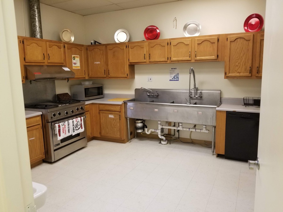 A spacious kitchen with wooden cabinets, a large sink, and various appliances.
