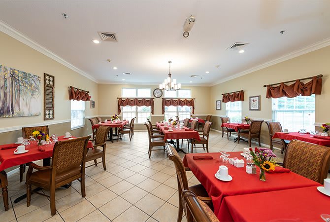 A well-decorated dining room with red tablecloths and neatly arranged tables and chairs.