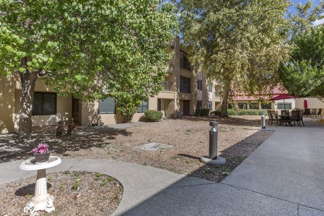 An outdoor view of an apartment building surrounded by trees and a pathway.