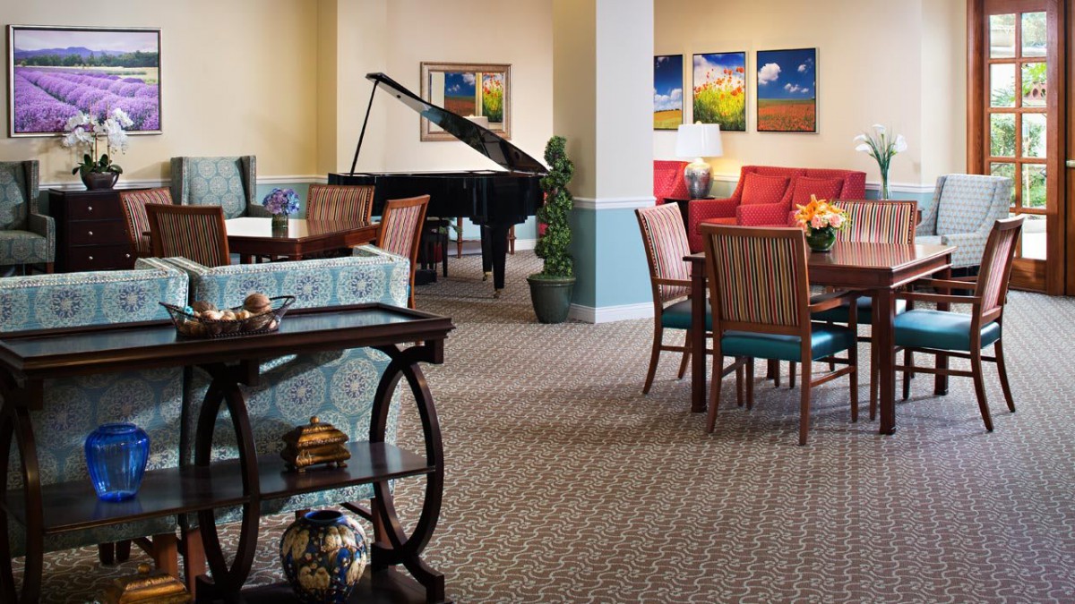 A cozy living room featuring a grand piano, seating area, and colorful artwork on the walls.
