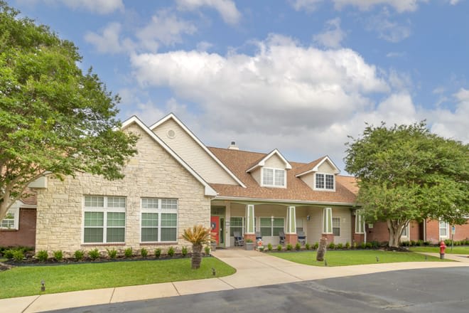 A suburban residential house with a well-maintained lawn and a cloudy sky.