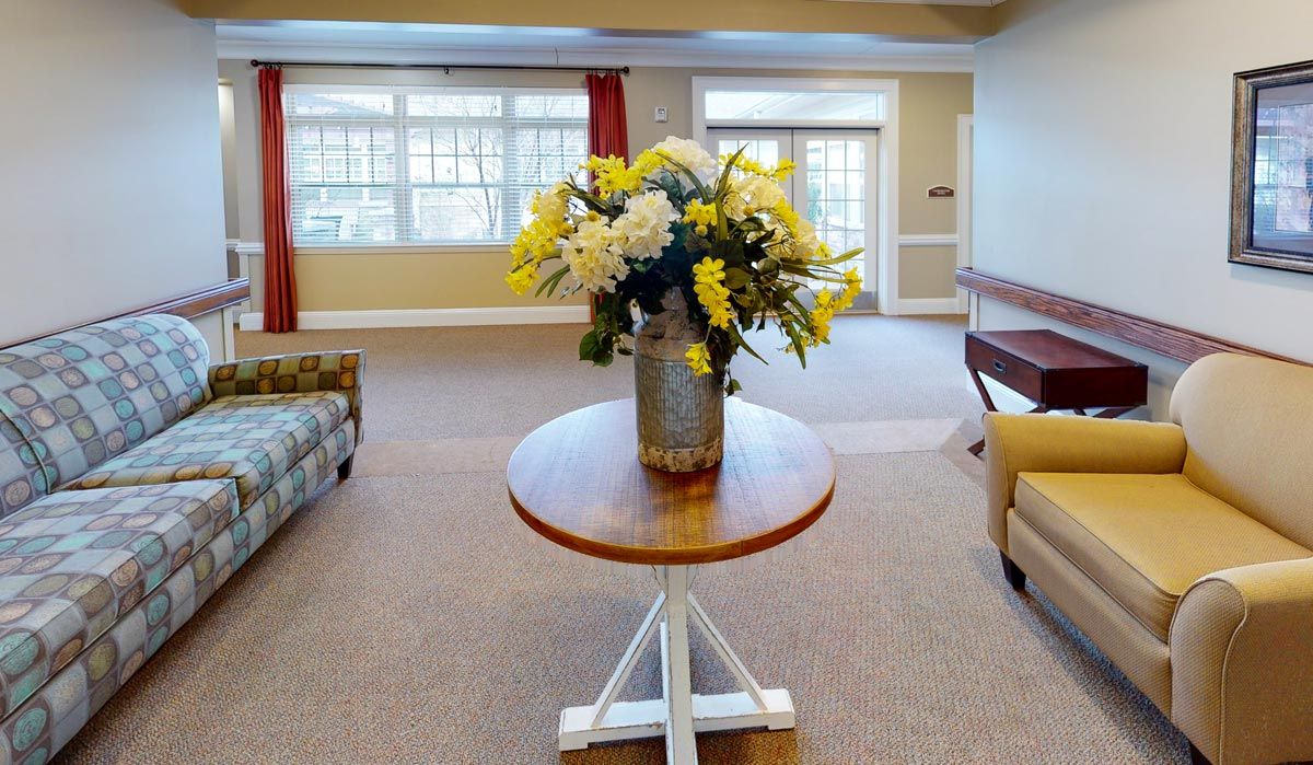 A cozy living room with a floral arrangement on a round table.
