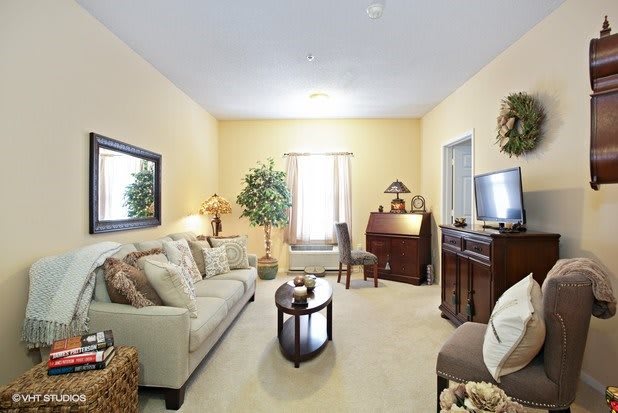 A cozy living room with a sofa, coffee table, and TV, featuring warm lighting and decorative elements.