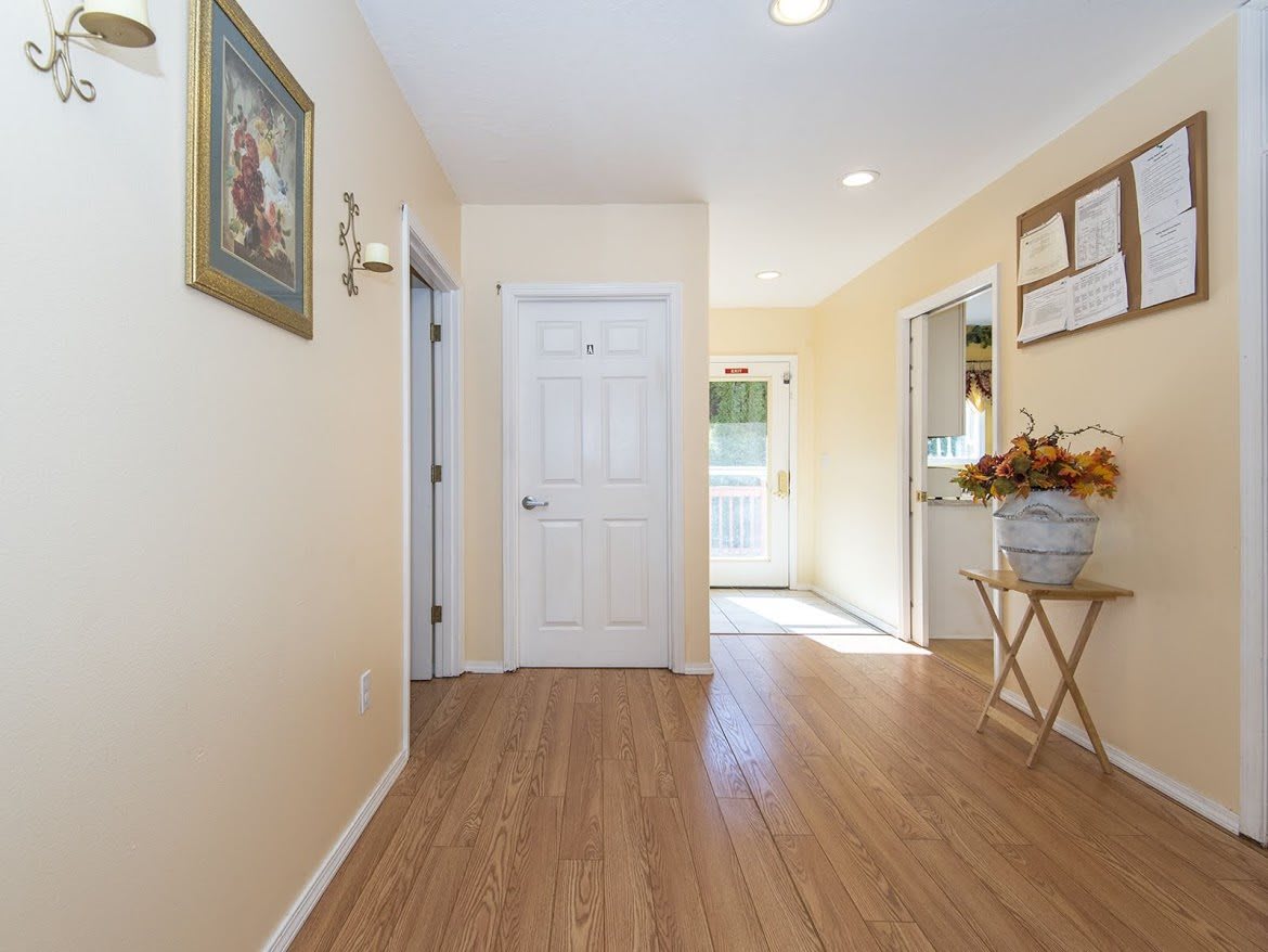 A well-lit hallway with wooden flooring and home decor.