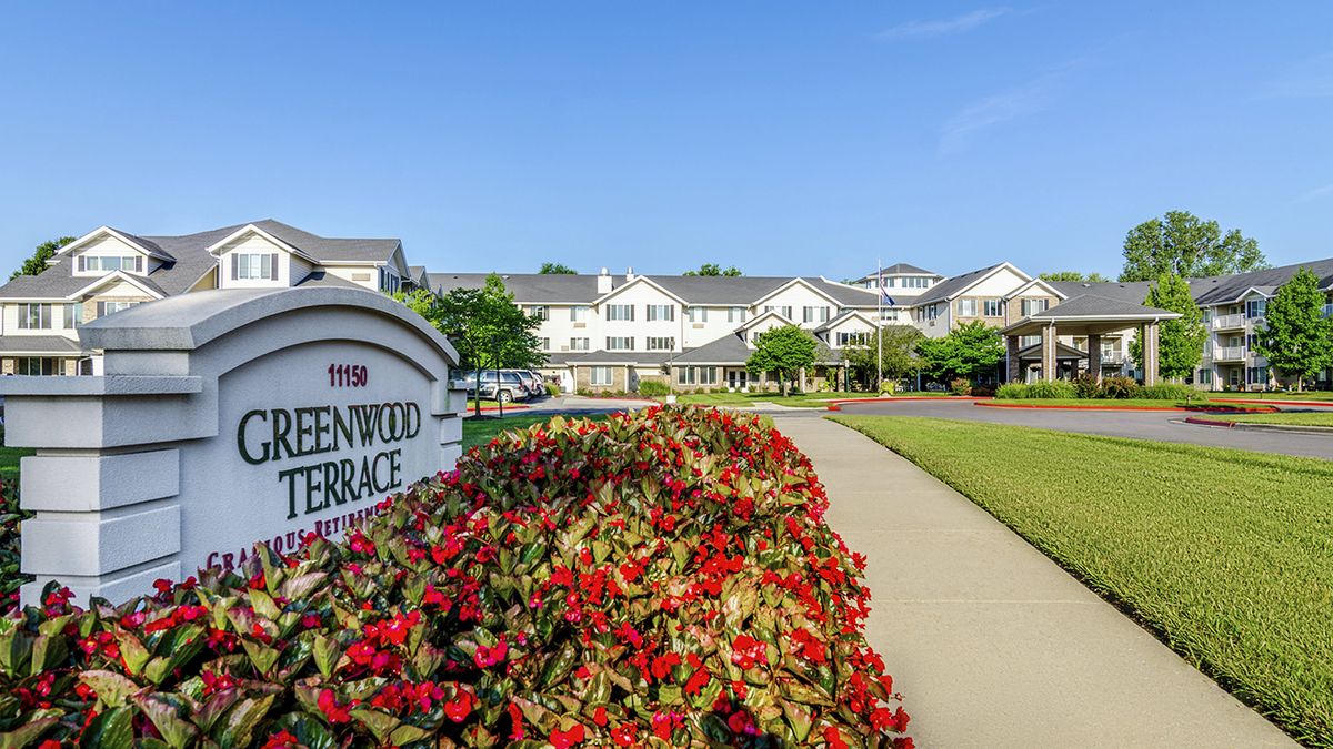 A view of a residential complex with well-maintained gardens and a welcoming entrance sign.