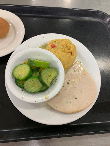A balanced meal featuring sliced turkey, steamed cucumbers, a savory muffin, and a bread roll.