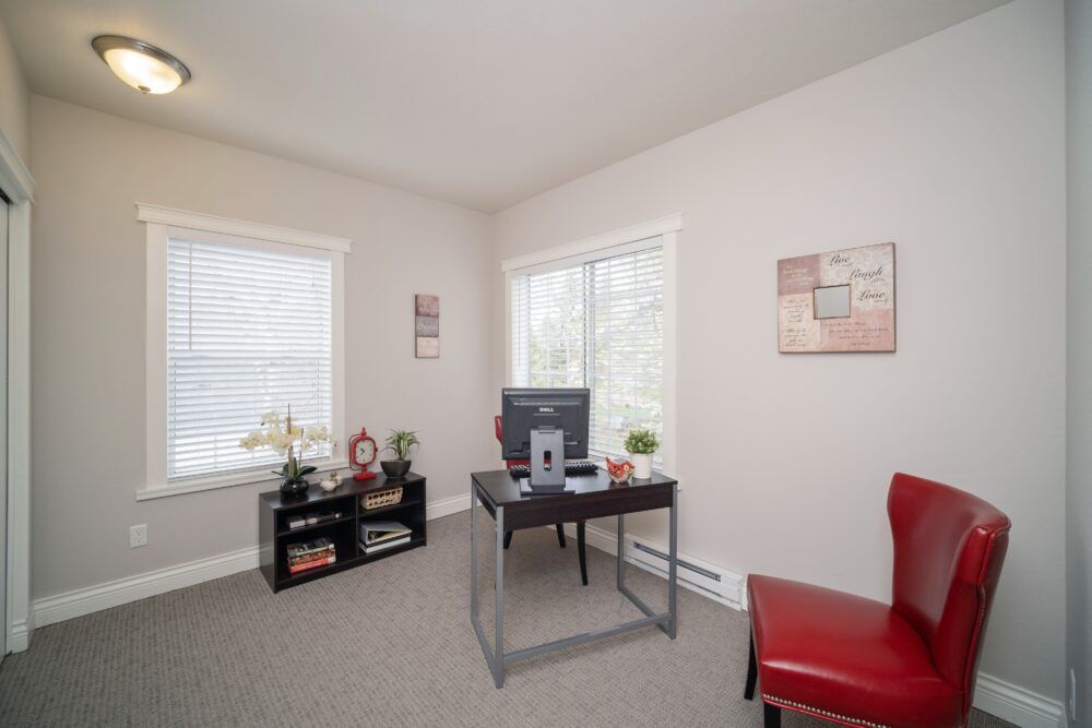 A bright and minimalist home office with a desk, chair, and computer, accented by decorative items.