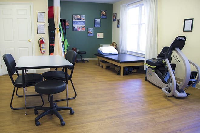 A physical therapy clinic room equipped with treatment table and exercise equipment.