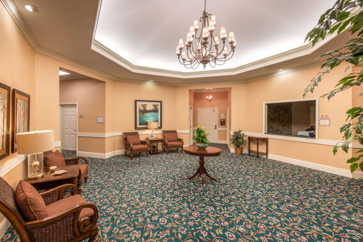 A well-decorated lobby featuring a central chandelier, elegant furniture, and a patterned carpet.
