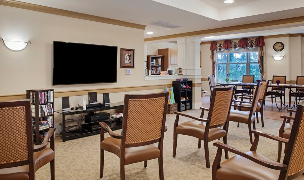 A cozy living area featuring several chairs arranged in front of a large television.