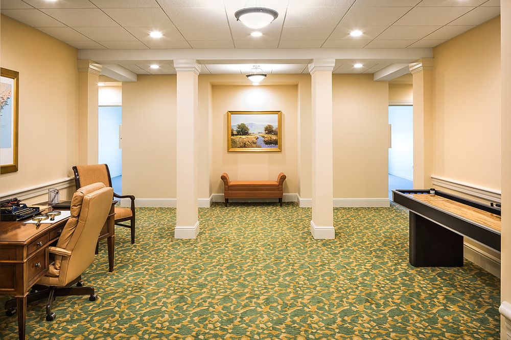 A well-lit hallway featuring seating and artwork with a carpeted floor.
