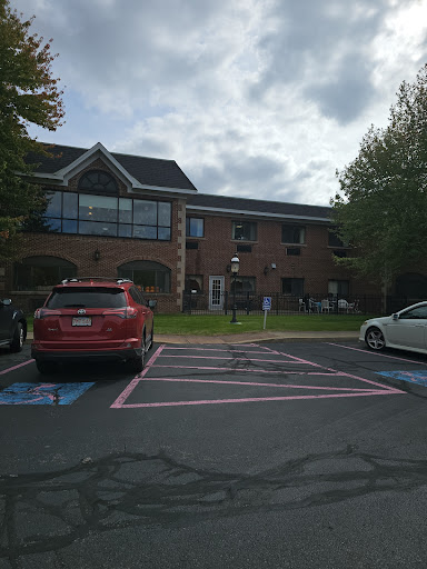 A view of a building with parked cars in front under a cloudy sky.