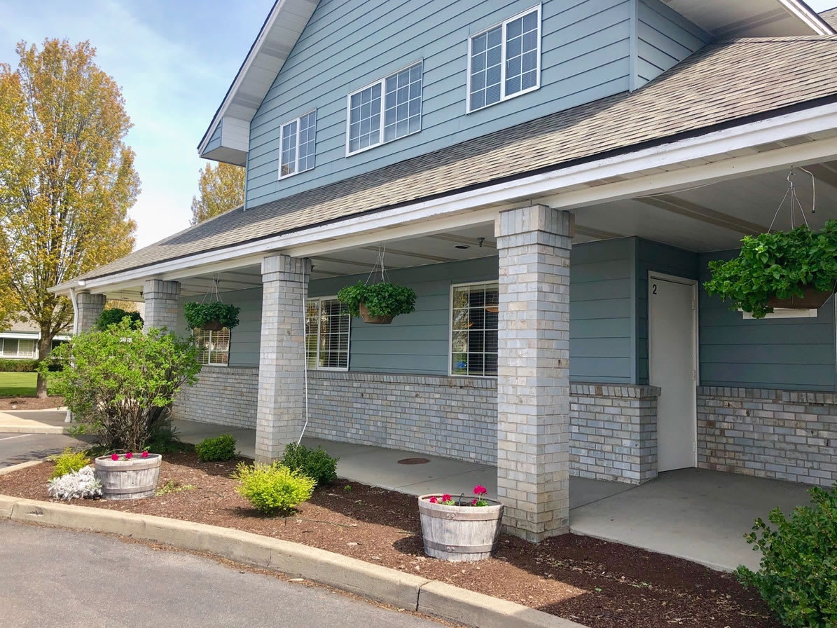 A blue house with a large porch, columns, and well-maintained landscaping.