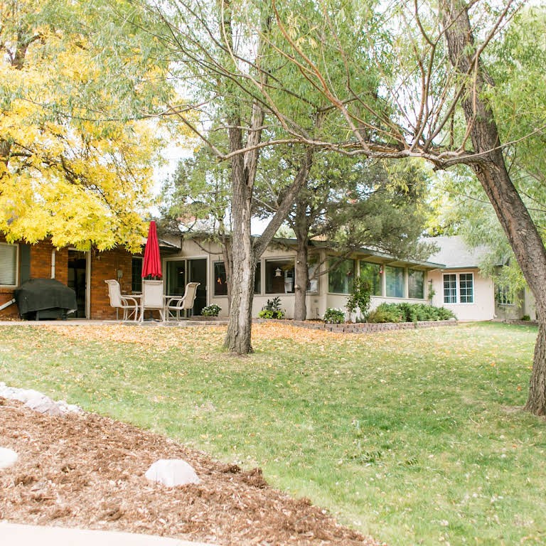 A cozy house surrounded by trees with an inviting patio area.