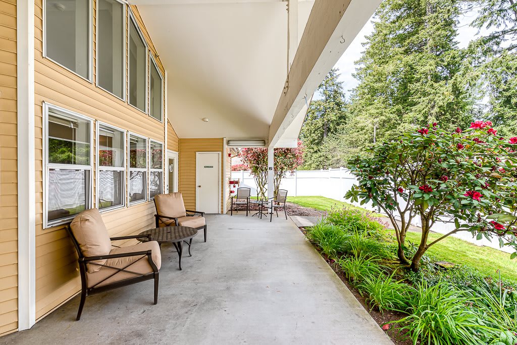 A cozy porch with comfortable seating and a view of a lush garden.