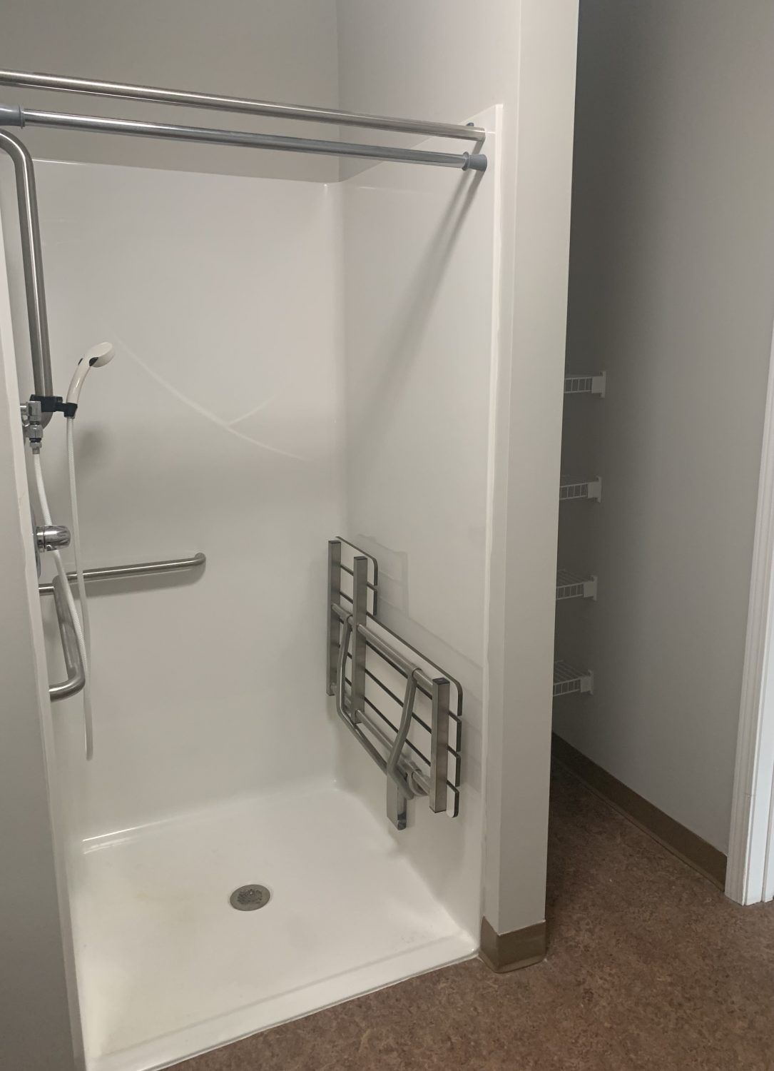 An accessible walk-in shower equipped with grab bars and a towel rack.