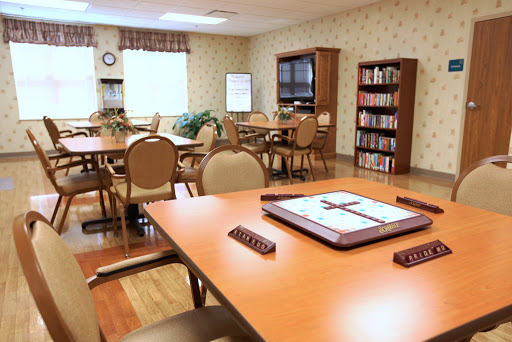 A well-furnished community room with tables and bookshelves, designed for group activities and reading.
