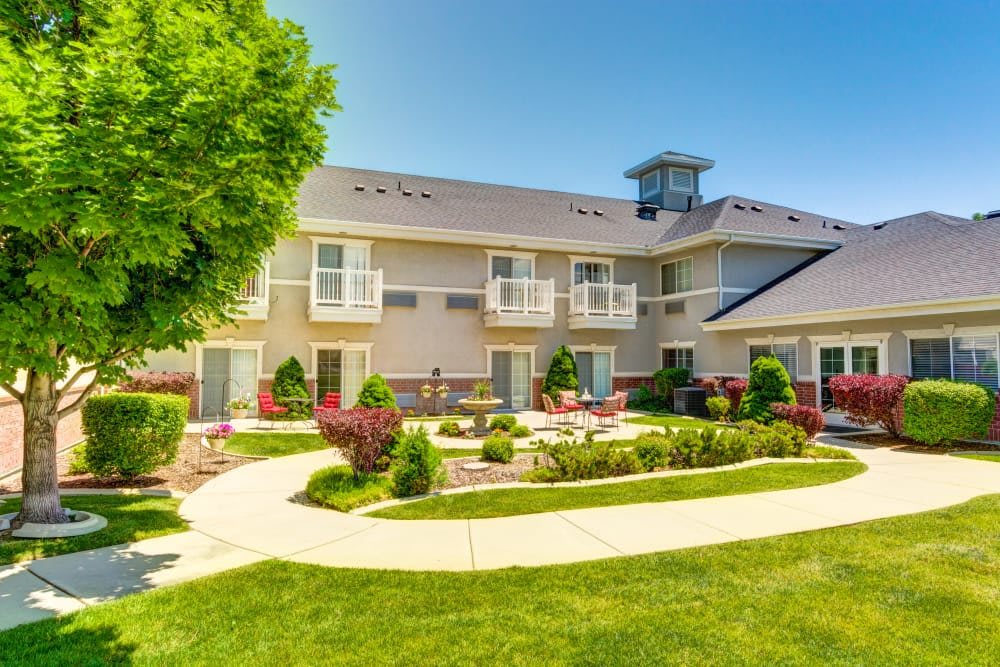 A well-maintained residential building with beautiful garden landscaping under a clear blue sky.