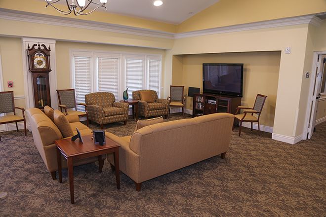 A cozy living room with a sofa, multiple chairs, a television, and a coffee table arranged on a carpeted floor.