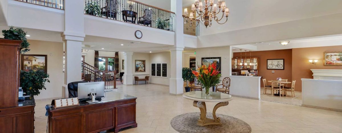 Elegant lobby with a grand chandelier and floral centerpiece on a round table.