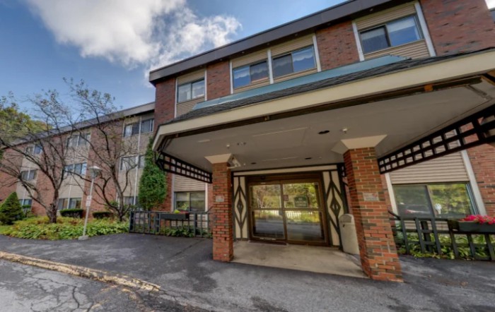A view of a residential building entrance with brick facade and a covered entryway.