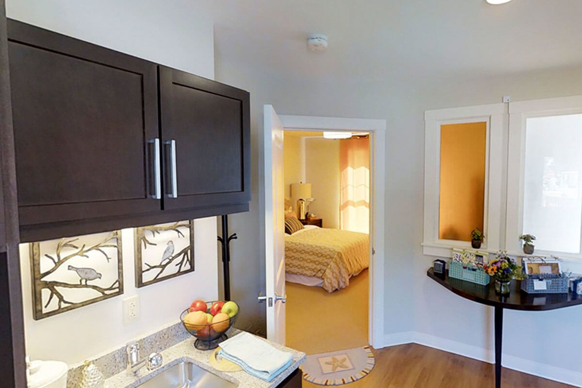 Modern kitchen area with a glimpse into a cozy bedroom.