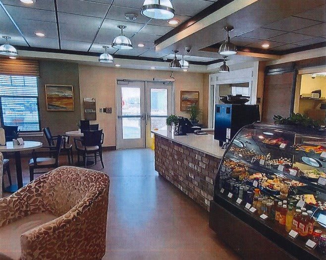 A cozy cafe interior with seating and a display case.
