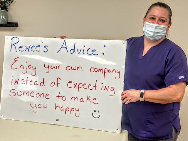 A nurse holding a sign with advice on enjoying your own company.
