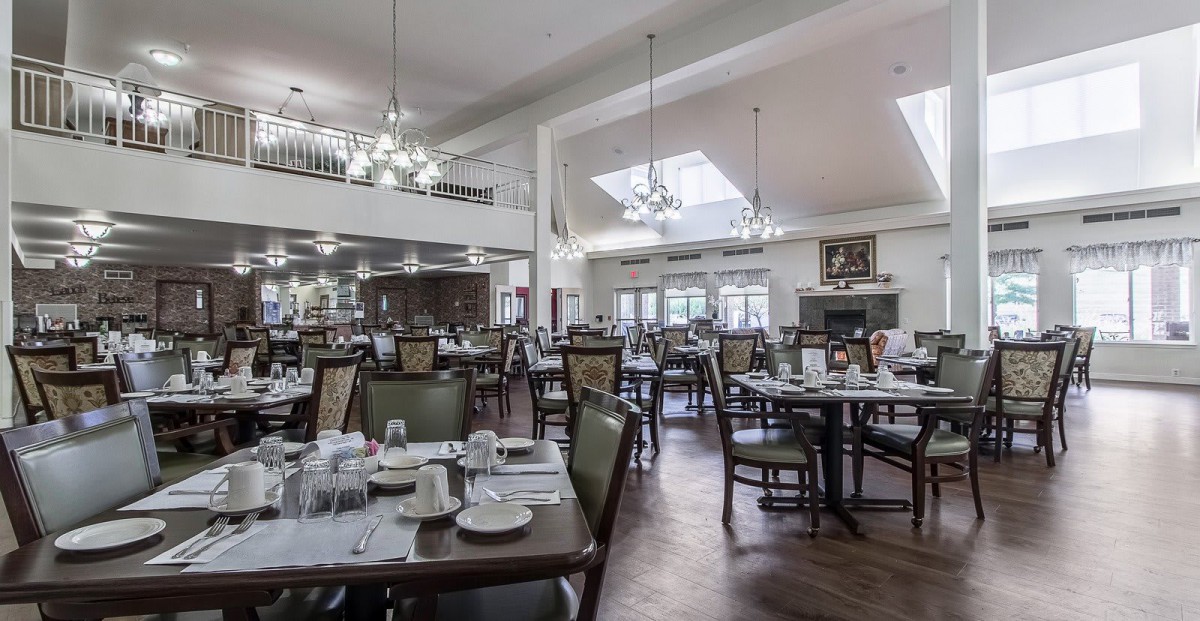 Spacious dining area with neatly arranged tables and elegant chandeliers.