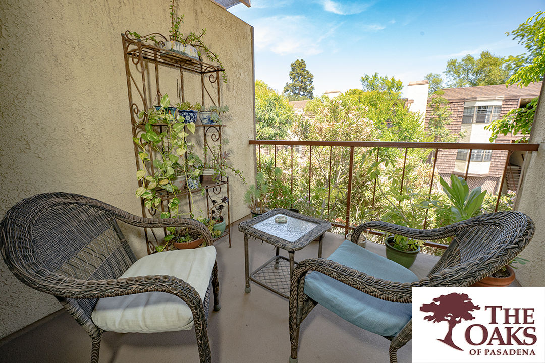 A cozy balcony with comfortable seating, adorned with plants and overlooking a lush garden.