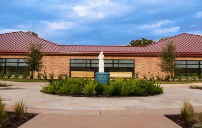 A building with a central statue surrounded by greenery.