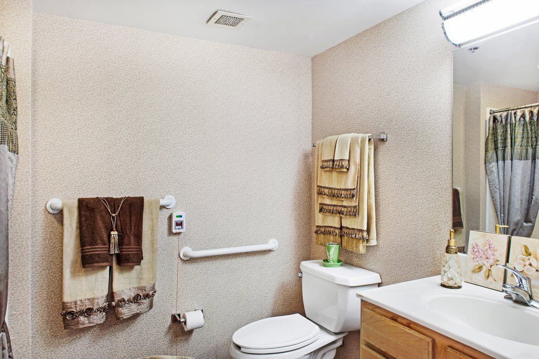 A neatly arranged bathroom with a toilet, sink, and towels in neutral tones.