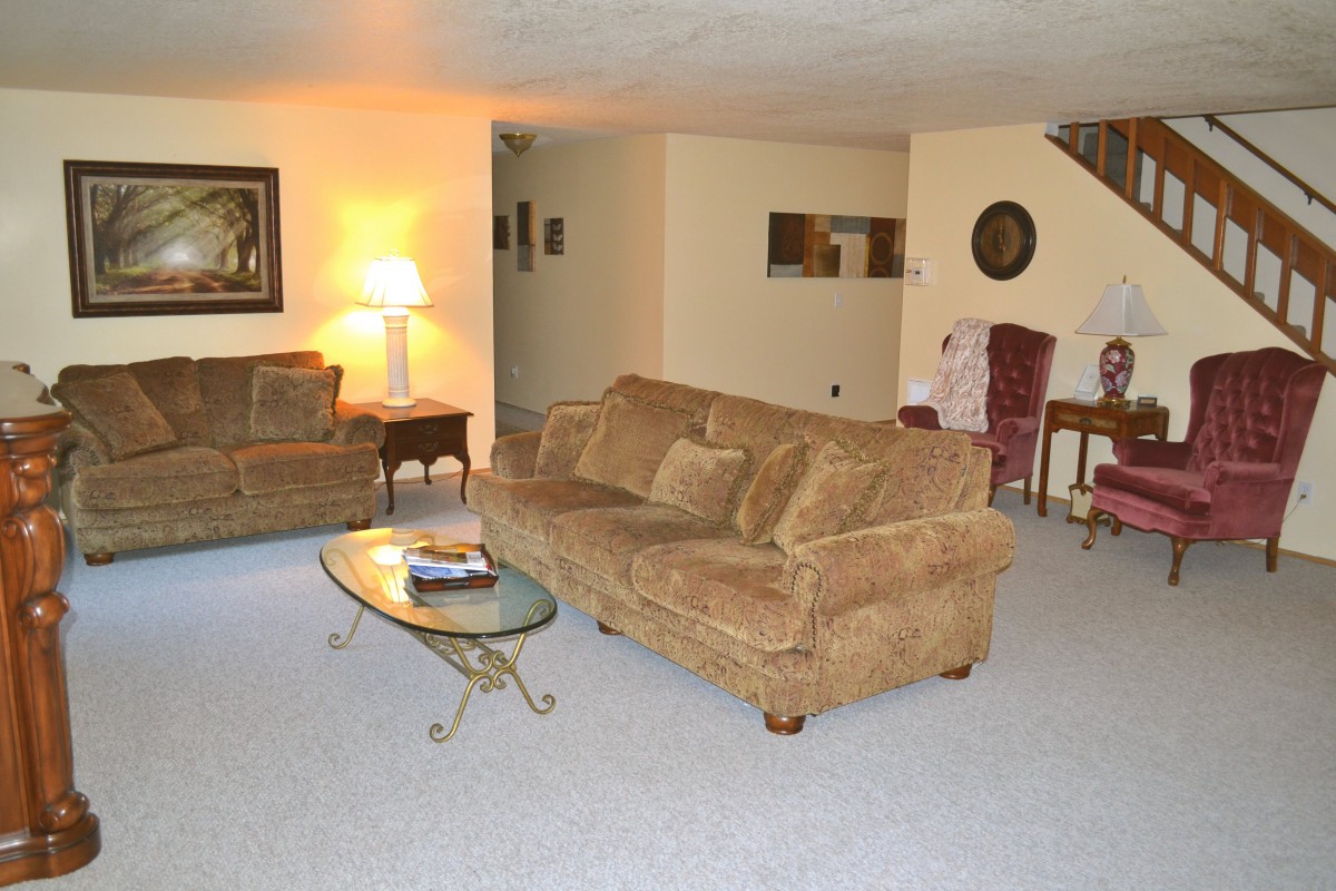 A cozy living room with a sofa, armchair, coffee table, and lamp.