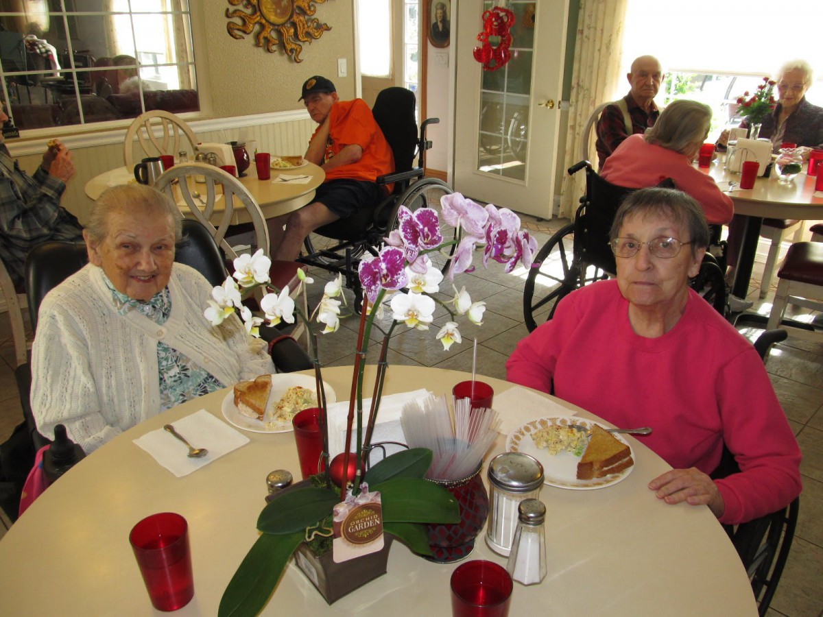 Elderly individuals enjoying a meal together in a dining area.