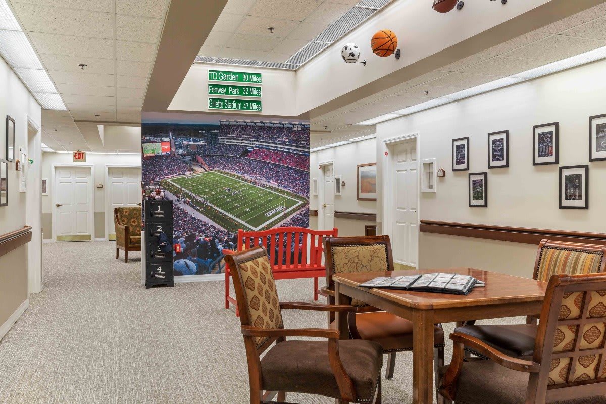 A sports-themed lounge area featuring a large football stadium mural, seating arrangements, and decorative elements on the walls and ceiling.