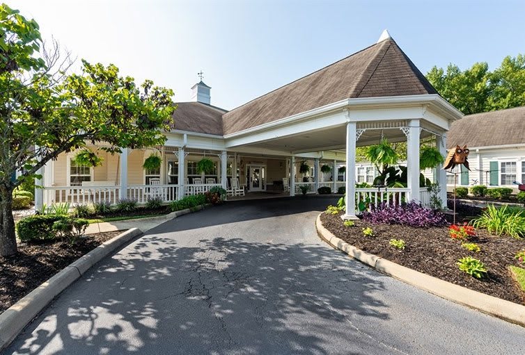 A welcoming view of a building entrance with a covered driveway and landscaped surroundings.