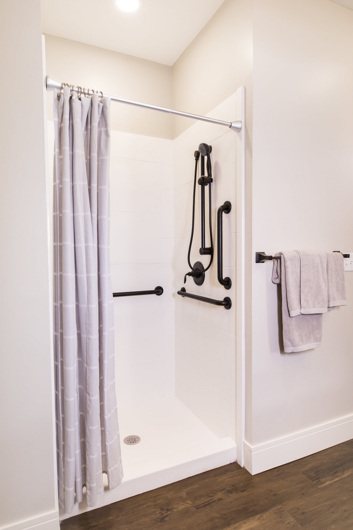 An accessible shower featuring grab bars and a shower curtain.