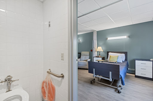 A view into a modern hospital patient room, featuring a clean shower area and comfortable furnishings.