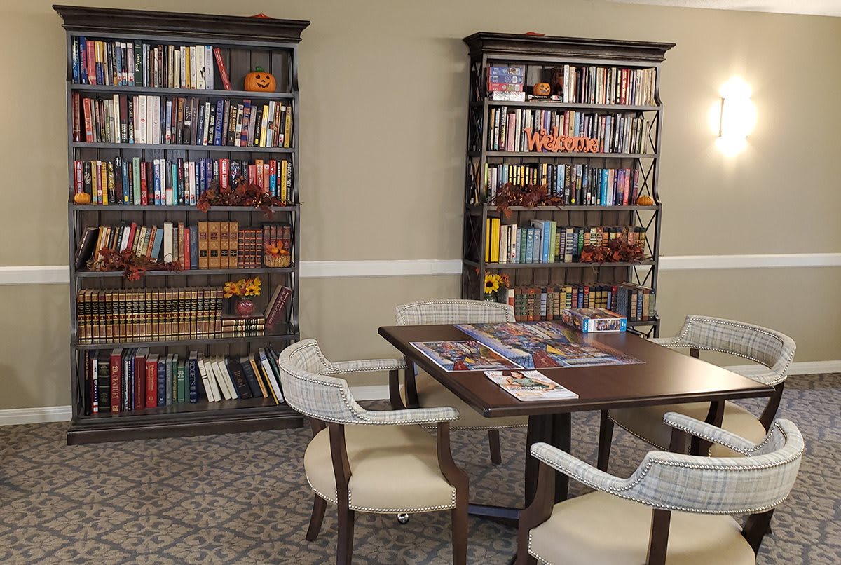 A cozy reading room featuring bookshelves filled with a variety of books, a table, and chairs.