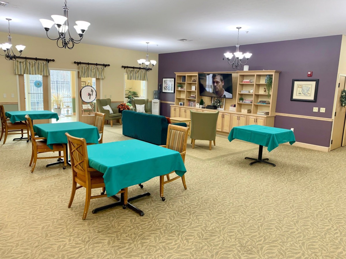A spacious dining area with tables and chairs, well-lit by chandeliers.