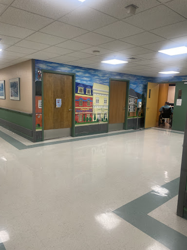 A well-lit hallway featuring doors and colorful murals on the walls.