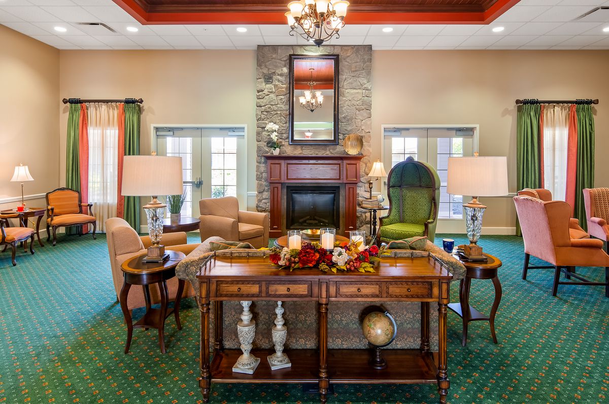 An elegantly decorated living room featuring a fireplace, armchairs, and a chandelier.
