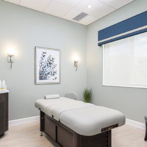 A serene and modern spa room with a massage table, soft lighting, and minimalistic decor.