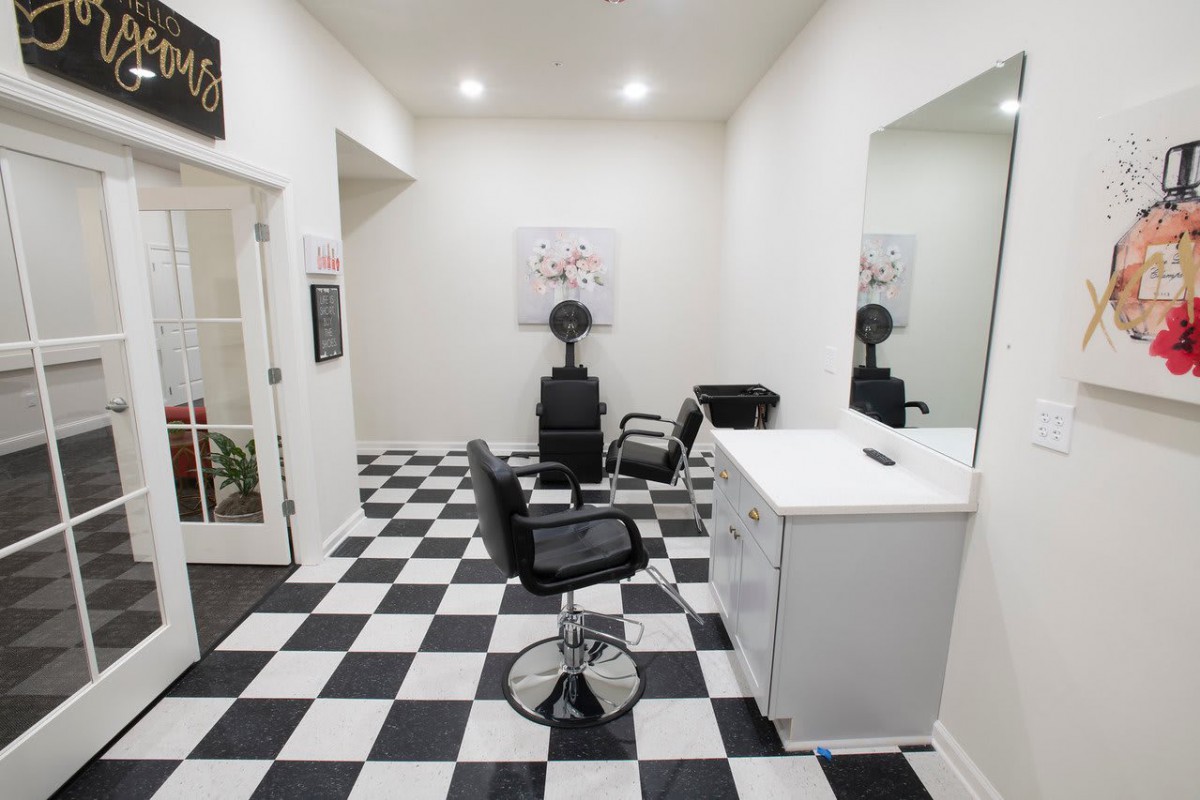 A tidy barbershop with a checkered floor and modern furnishings.