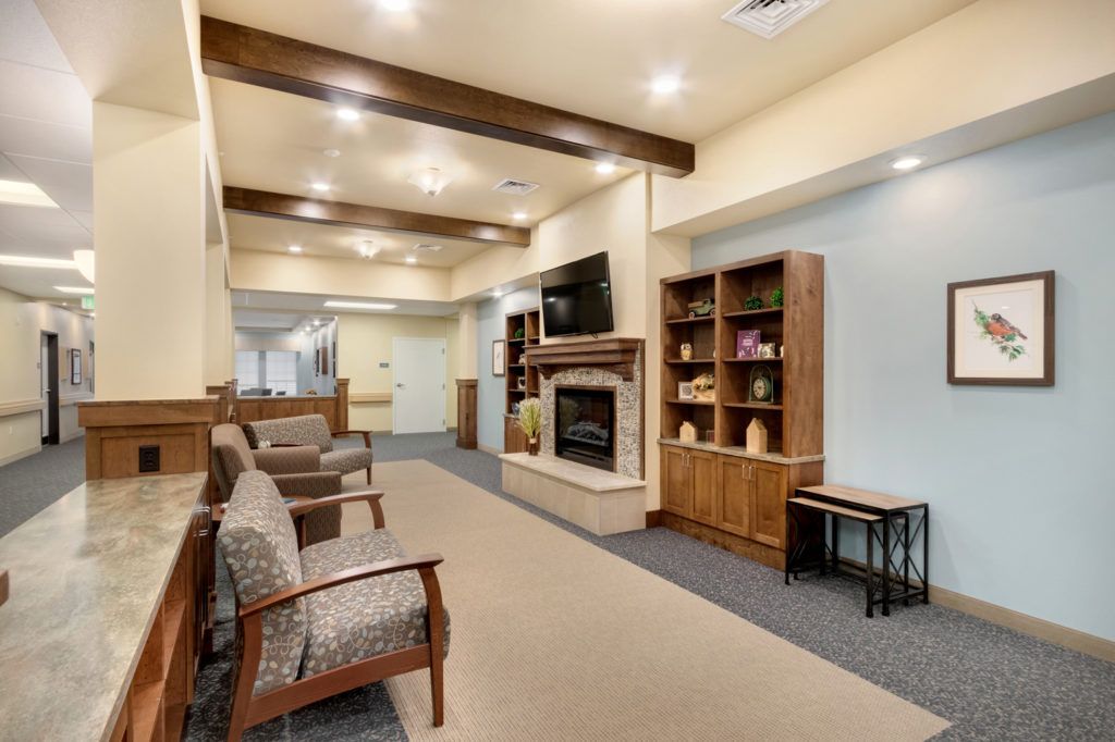 A cozy living room featuring cushioned chairs, a fireplace, and a wooden bookshelf.