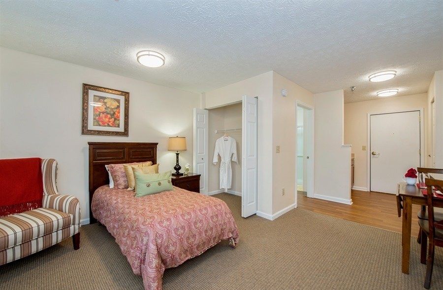 A cozy bedroom with a single bed, artwork on the wall, and an open closet.