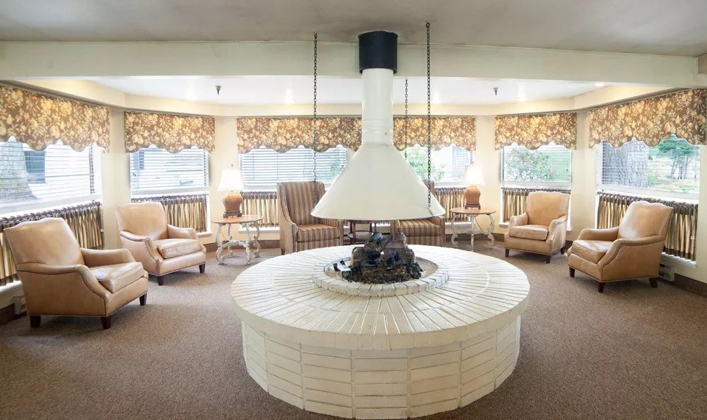 A vintage-style lounge with a central fireplace and cozy seating arrangement.
